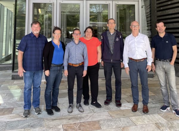 Group of scientists standing in front of glass doors